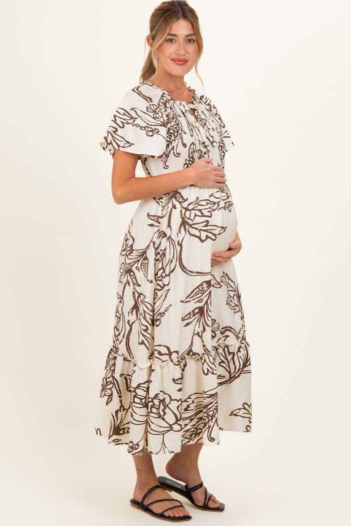 woman wearing a cream floral print maternity dress with flutter sleeves and a visible baby bump