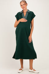 woman wearing a dark green maternity dress with a striped collar and holding her baby bump