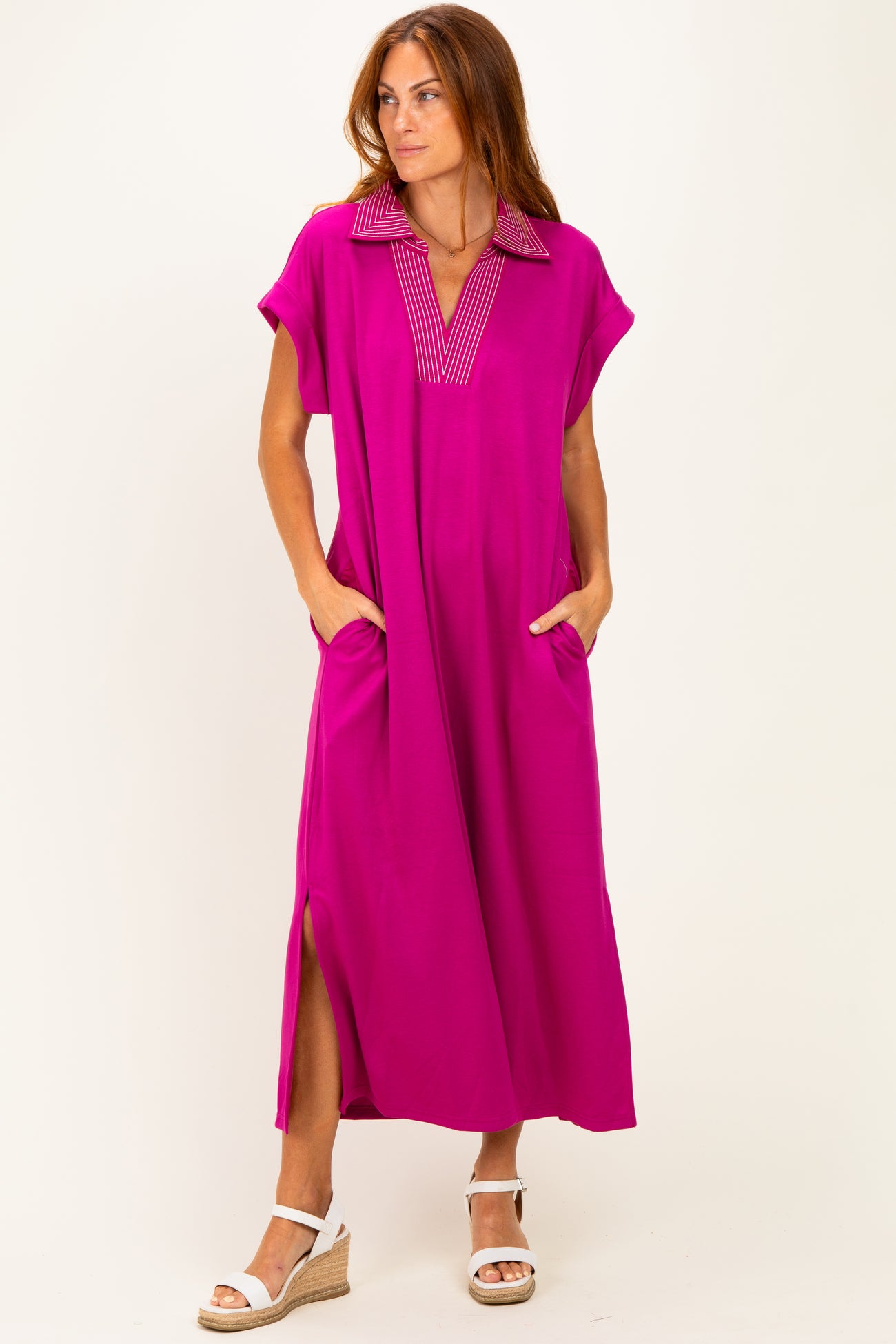 woman wearing a bright pink maxi dress with a collar and side pockets, standing against a white background