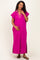 woman wearing a hot pink maternity maxi dress with a collar and side slits, gently cradling her baby bump