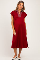 woman wearing a red maternity dress with a striped collar and side slits, showing her baby bump