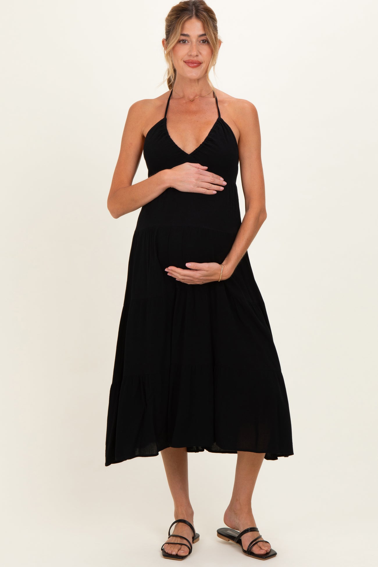 woman wearing a black halter maternity dress and holding her baby bump