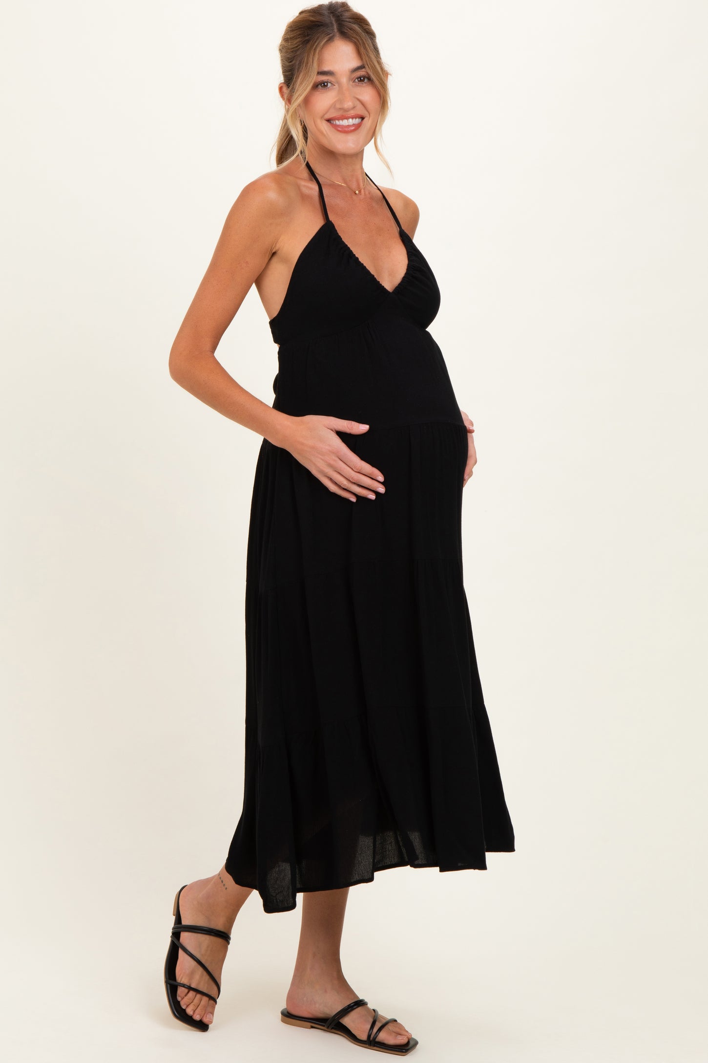 woman wearing a black halter neck maternity dress and holding her baby bump