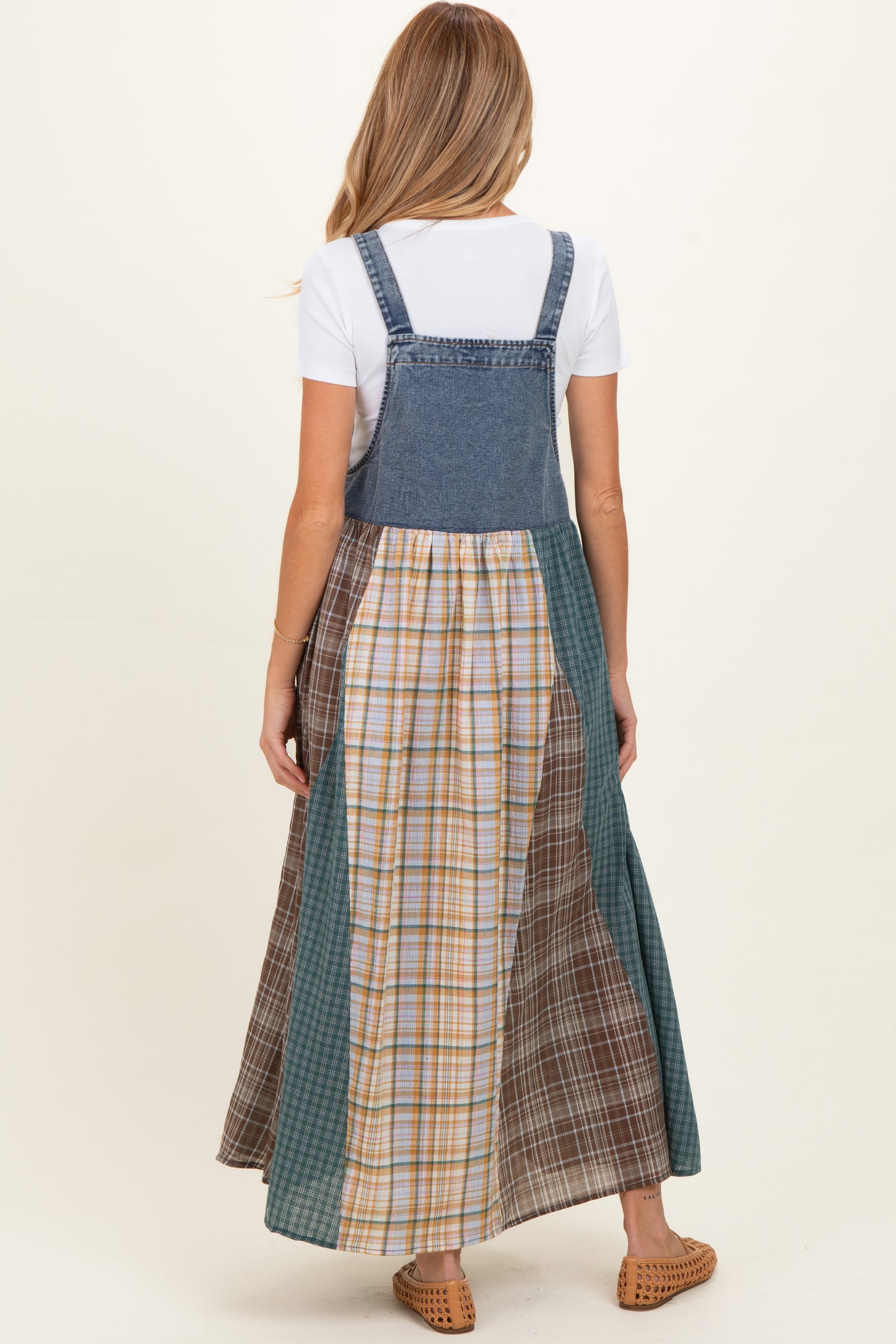 woman wearing a denim maternity maxi dress with a plaid and gingham patchwork skirt, showing a baby bump