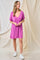 woman wearing a pink short sleeve v-neck dress paired with white sneakers, standing against a neutral background