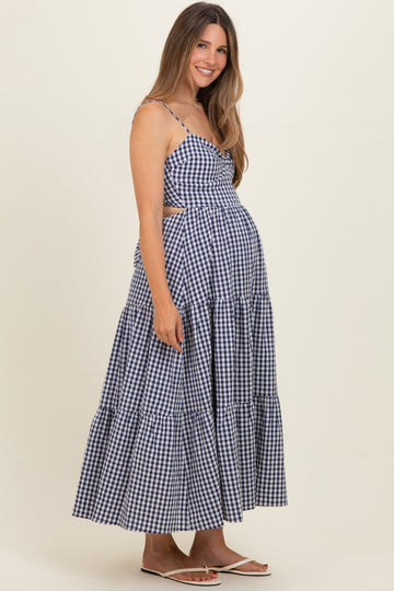 woman wearing a navy and white gingham maternity dress with cut-out details and a tiered skirt, showcasing her baby bump
