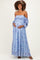 woman wearing a light blue off-the-shoulder floral maternity dress and cradling her baby bump