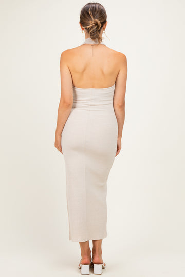 woman wearing a beige ribbed halter neck maternity dress, showing off her baby bump from the back