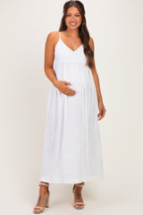 woman wearing a white maternity maxi dress with spaghetti straps and holding her baby bump