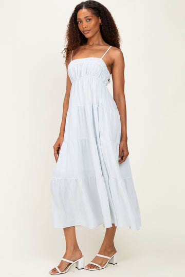 woman wearing a light blue striped tiered maxi dress with spaghetti straps