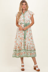 woman wearing a floral midi dress with cap sleeves and a tie waist in shades of orange and green
