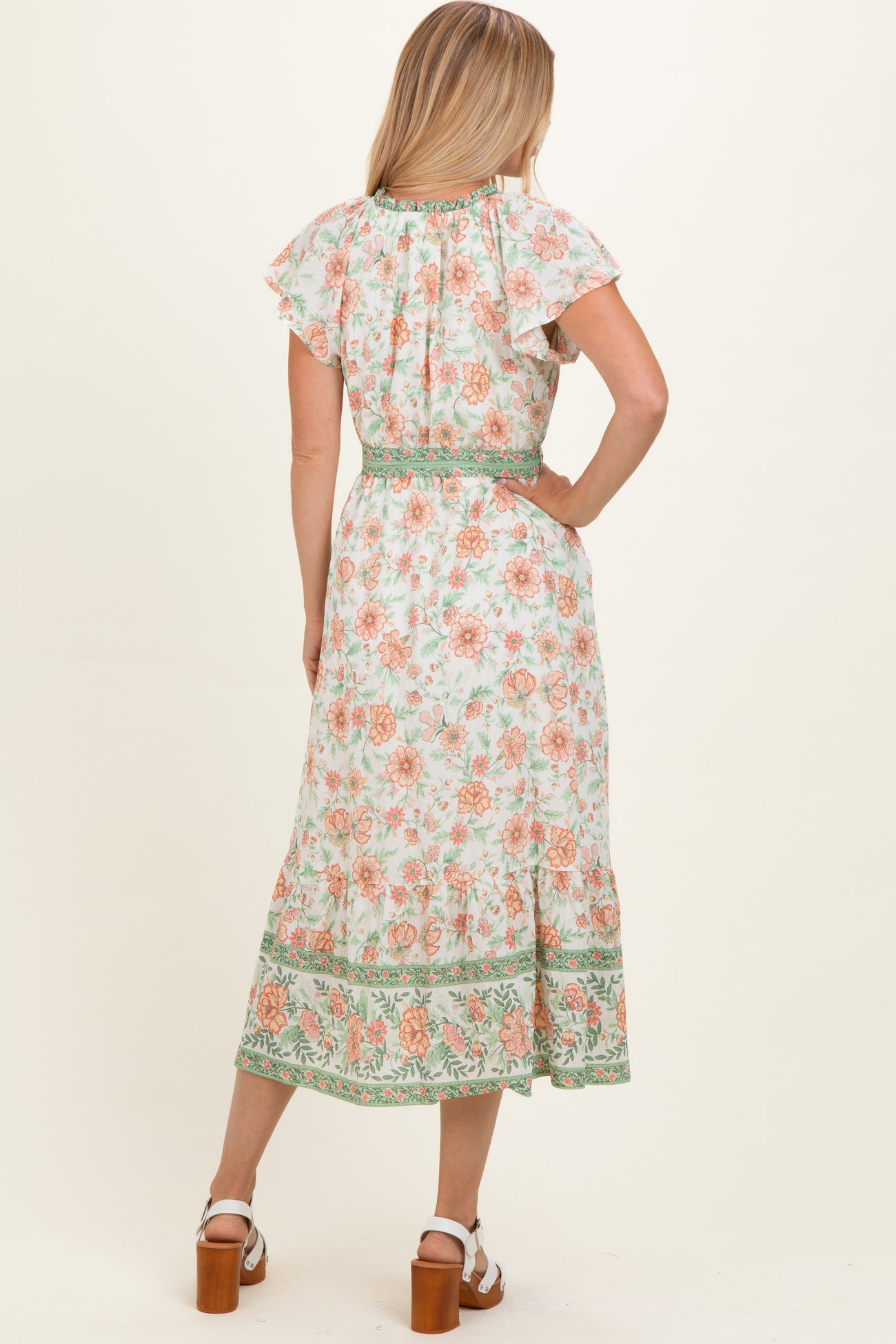 woman wearing a floral midi dress with ruffled sleeves and a cinched waist, viewed from the back