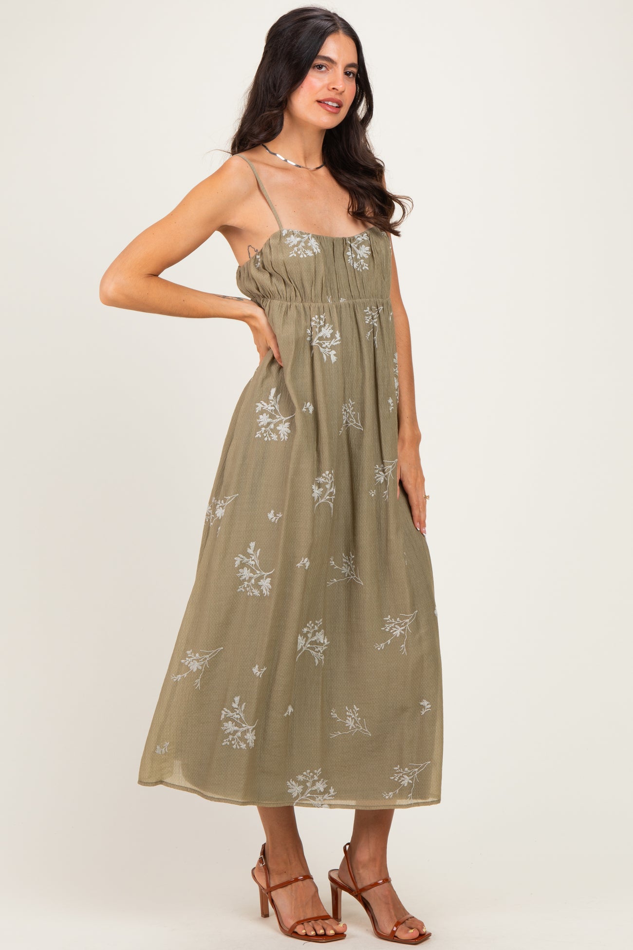 woman wearing an olive green floral maxi dress with spaghetti straps and a smocked bodice, posing sideways
