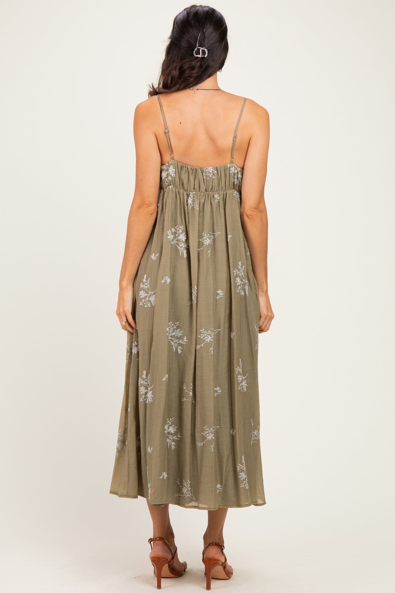 woman wearing an olive green floral midi dress with adjustable spaghetti straps, showing the back view