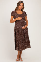 woman wearing a brown polka dot maternity dress and holding her baby bump