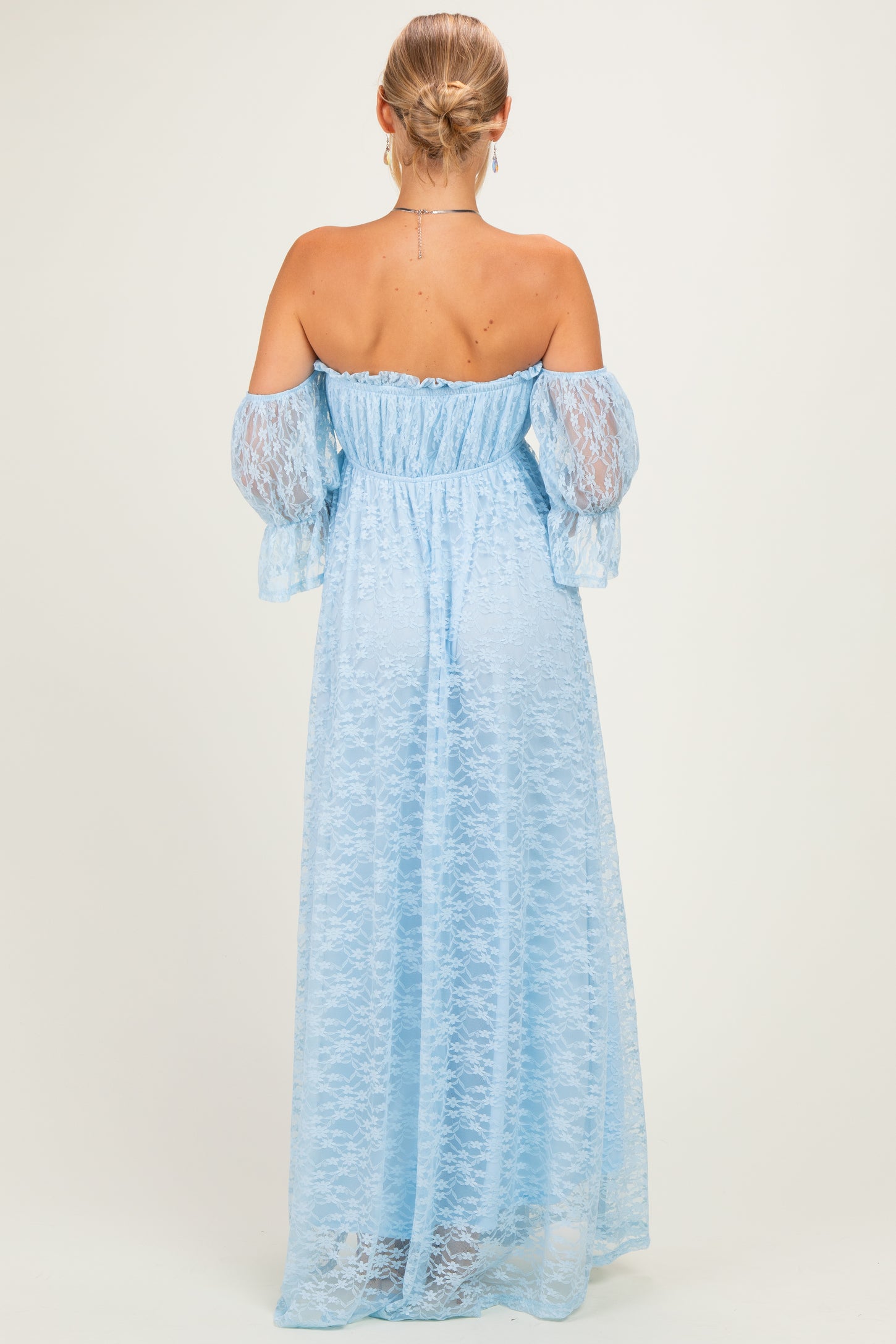 woman wearing a light blue off-the-shoulder maxi dress with lace details and long puff sleeves