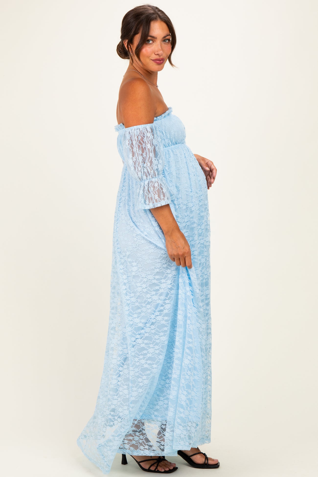 woman wearing a light blue off-the-shoulder lace maternity dress with a visible baby bump