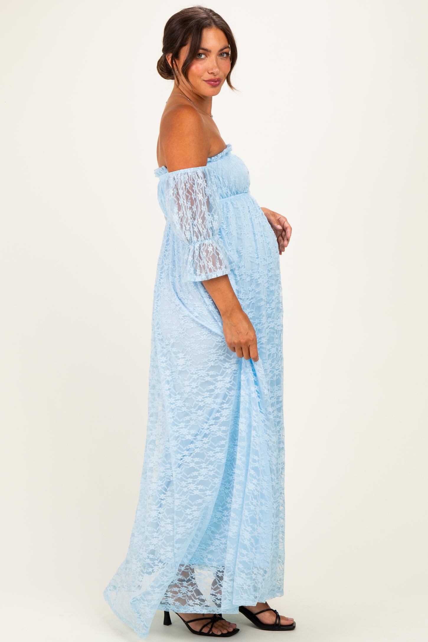 woman wearing a light blue off-the-shoulder lace maternity dress with a visible baby bump