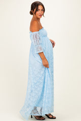 woman wearing a light blue off-the-shoulder lace maternity dress with a visible baby bump