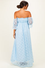 woman wearing a light blue off-the-shoulder maternity gown with sheer lace sleeves and a flowing skirt