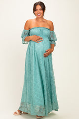 woman wearing a light blue off-the-shoulder maternity maxi dress and holding her baby bump
