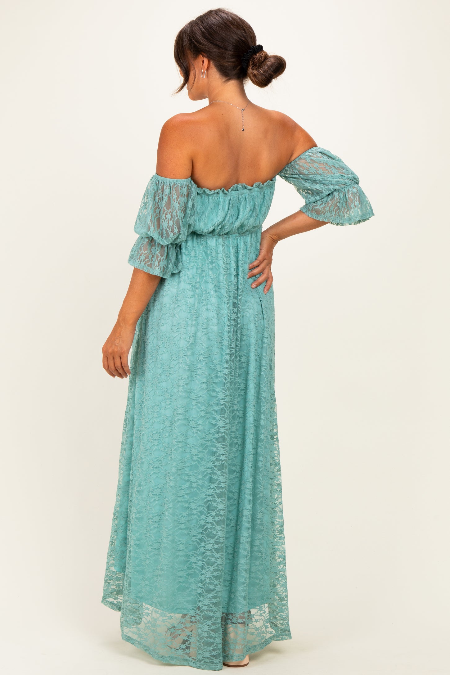 woman wearing a teal off-shoulder lace maternity maxi dress with flutter sleeves and a cinched waist