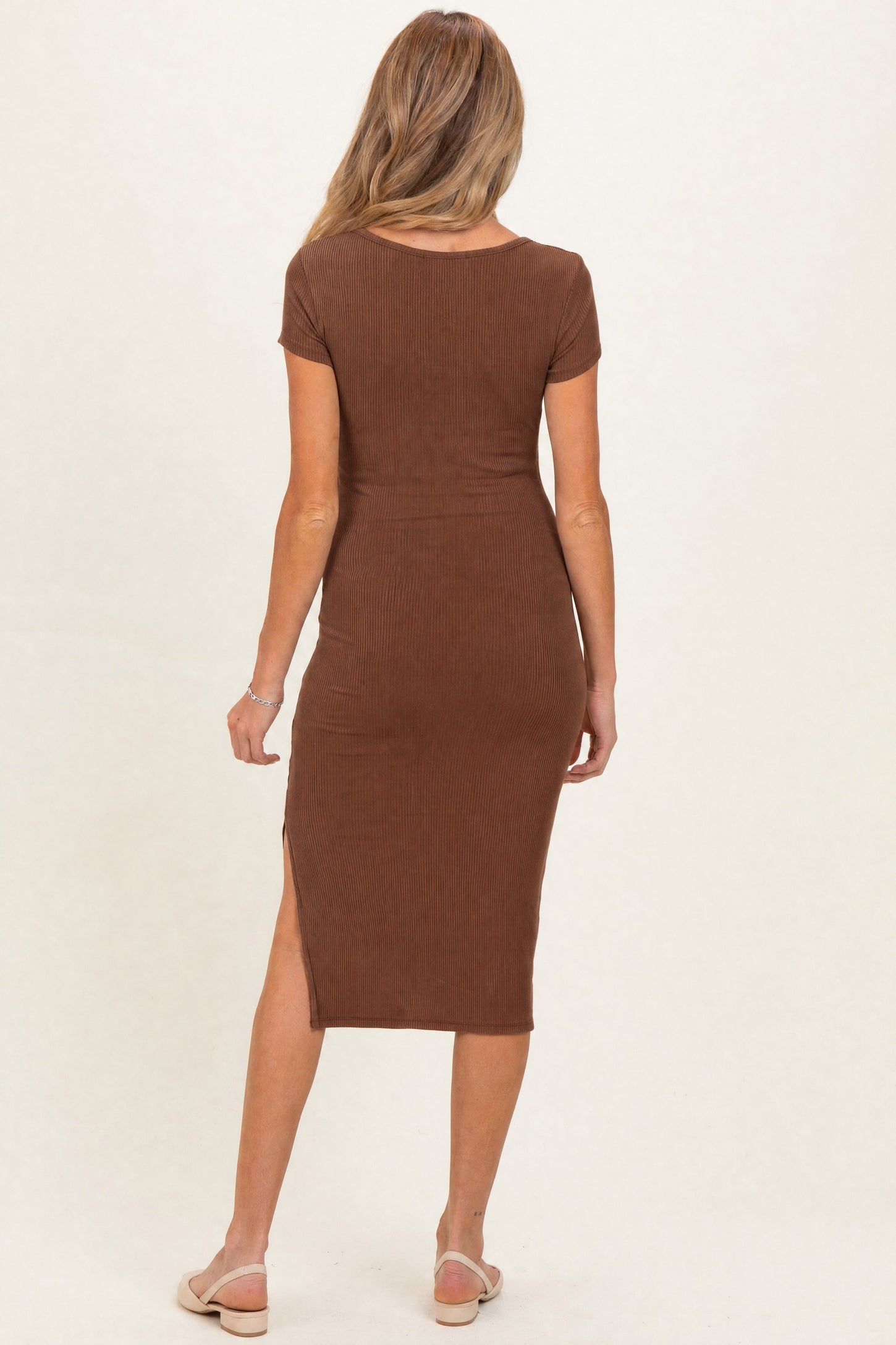 woman wearing a brown ribbed maternity dress with short sleeves and a side slit, showcasing her baby bump