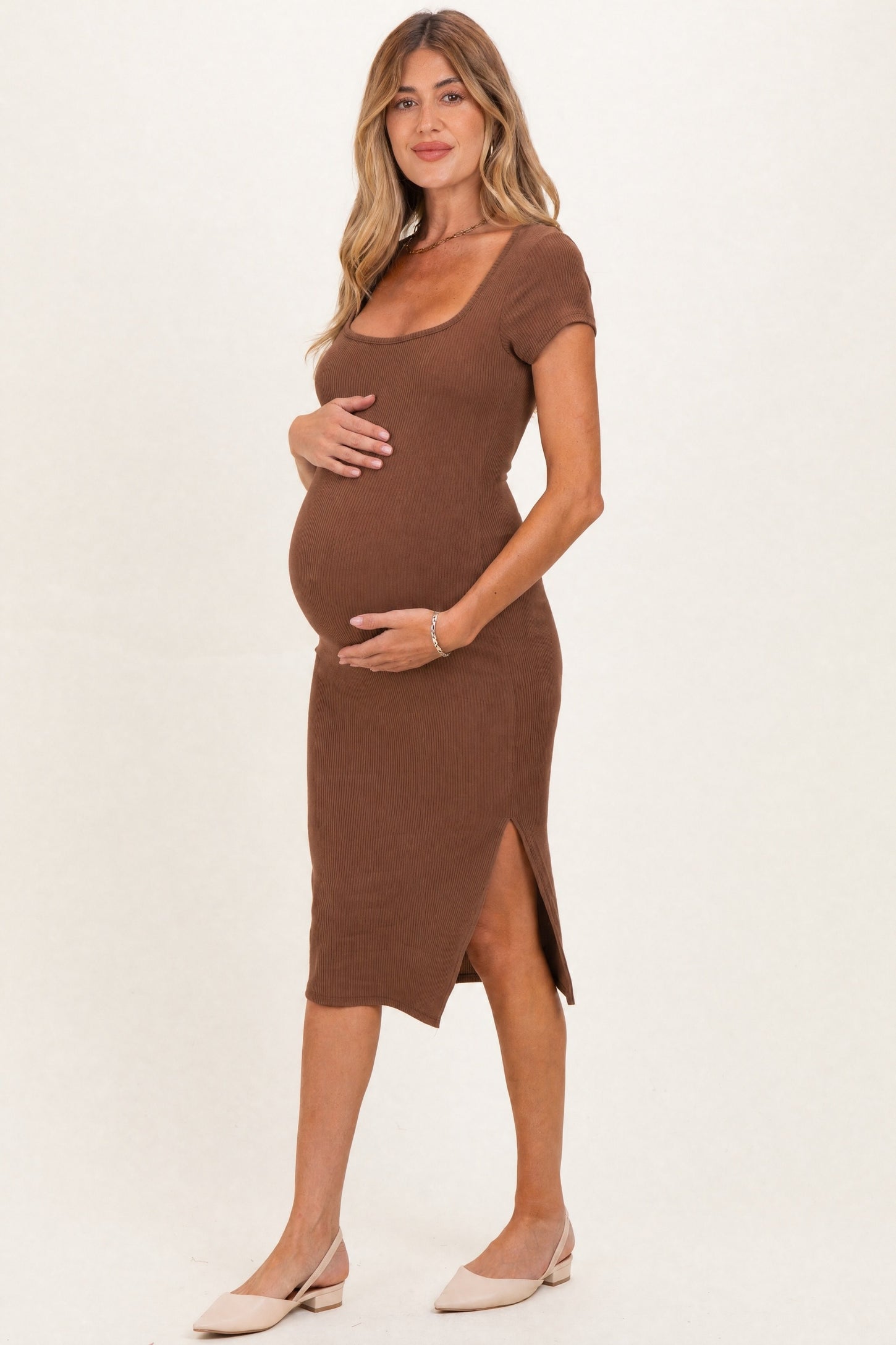 woman wearing a brown ribbed maternity dress with short sleeves and a side slit, showing a baby bump
