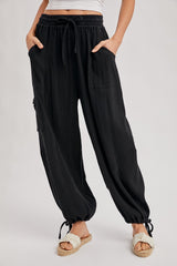 woman wearing black relaxed fit pants with pockets and drawstring hem, paired with white sandals