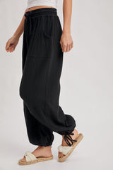 woman wearing black wide-leg lounge pants with a drawstring waist and side pockets, paired with fuzzy slippers