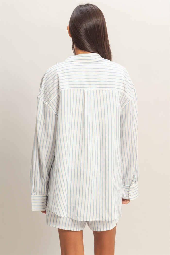 woman wearing a white and light blue striped oversized shirt, viewed from the back