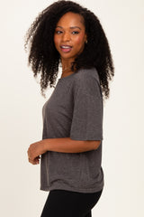 woman wearing a dark gray oversized short sleeve top paired with black leggings and smiling softly to the side