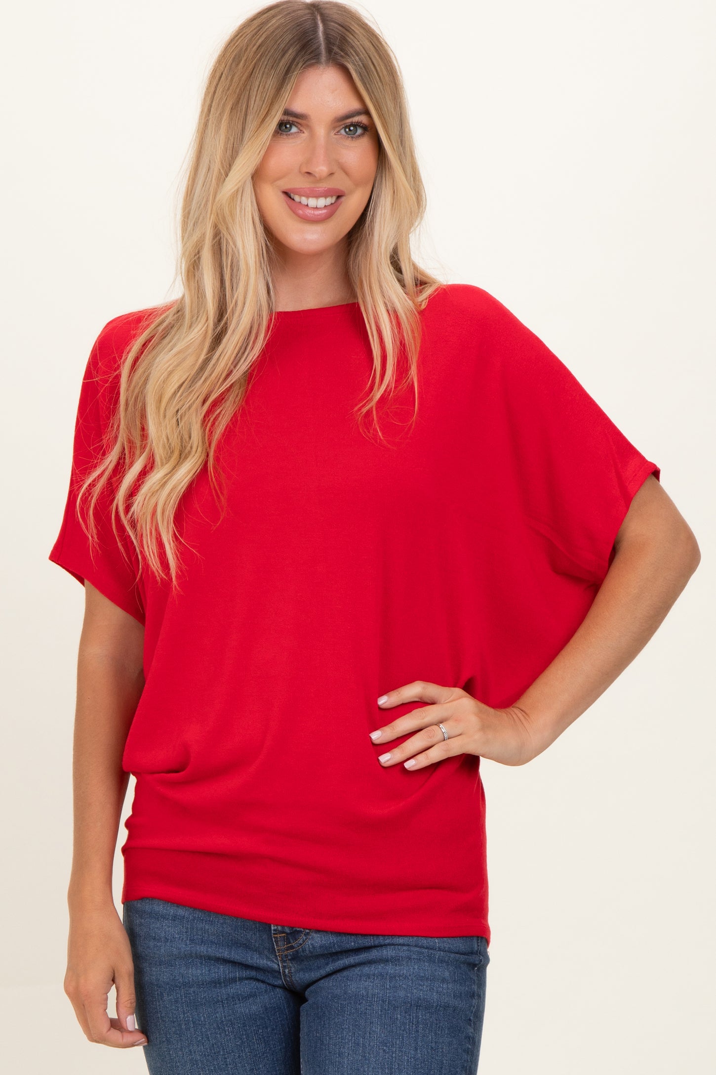 woman wearing a red short sleeve top with a loose fit and smiling at the camera
