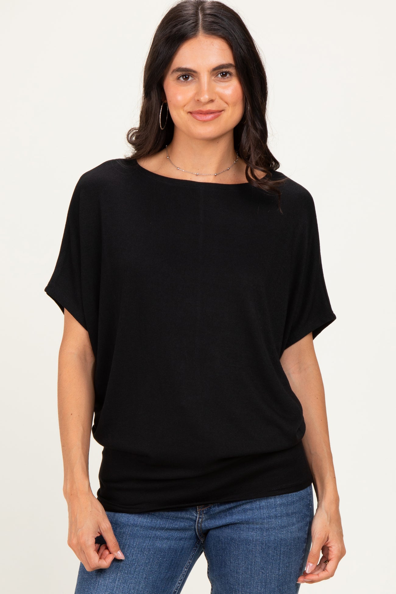 woman wearing a black loose fit short sleeve top with a rounded neckline and styled with blue jeans