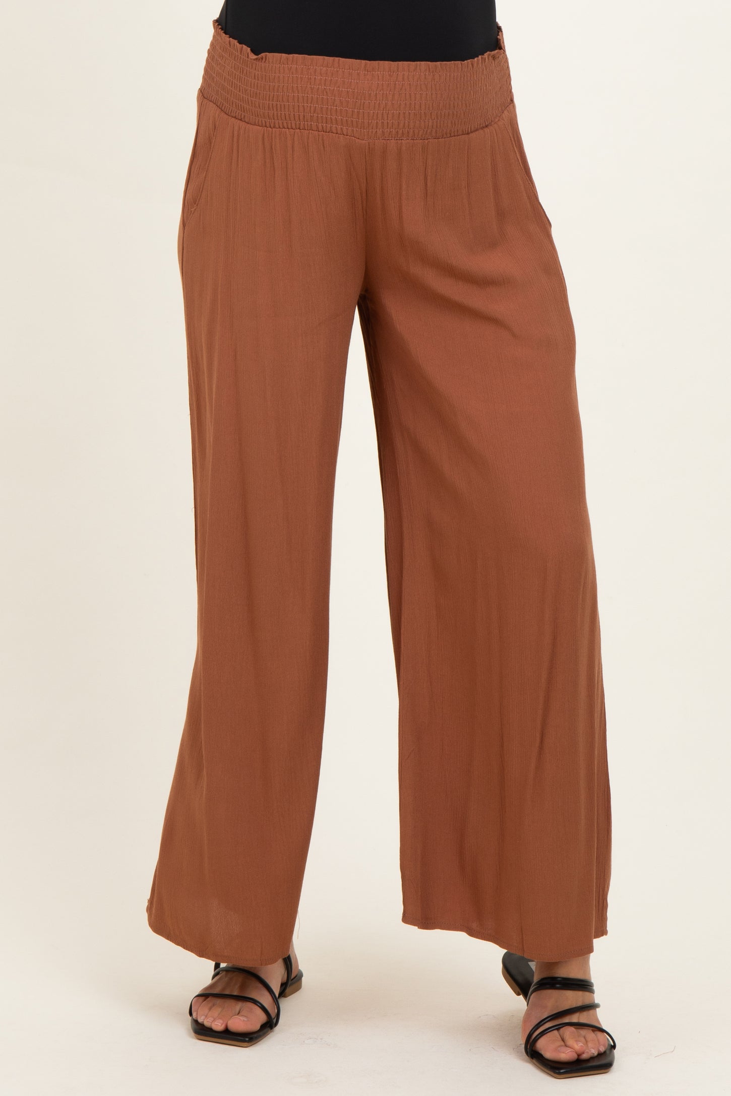 woman wearing brown wide leg maternity pants with a smocked waistband and loose fit