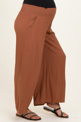 woman wearing rust-colored maternity wide-leg pants with a smocked waistband and side pockets