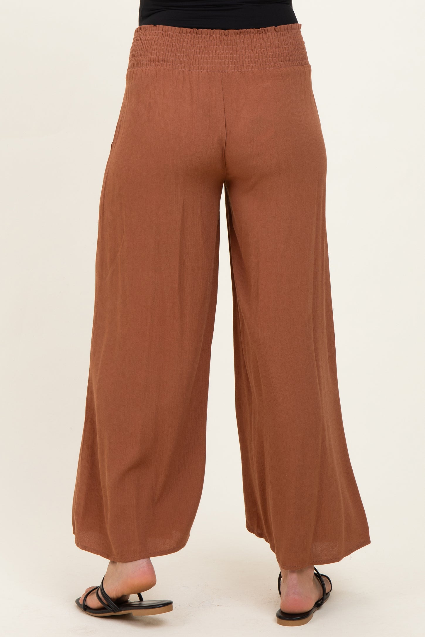 woman wearing brown maternity palazzo pants with a comfortable waistband, seen from the back