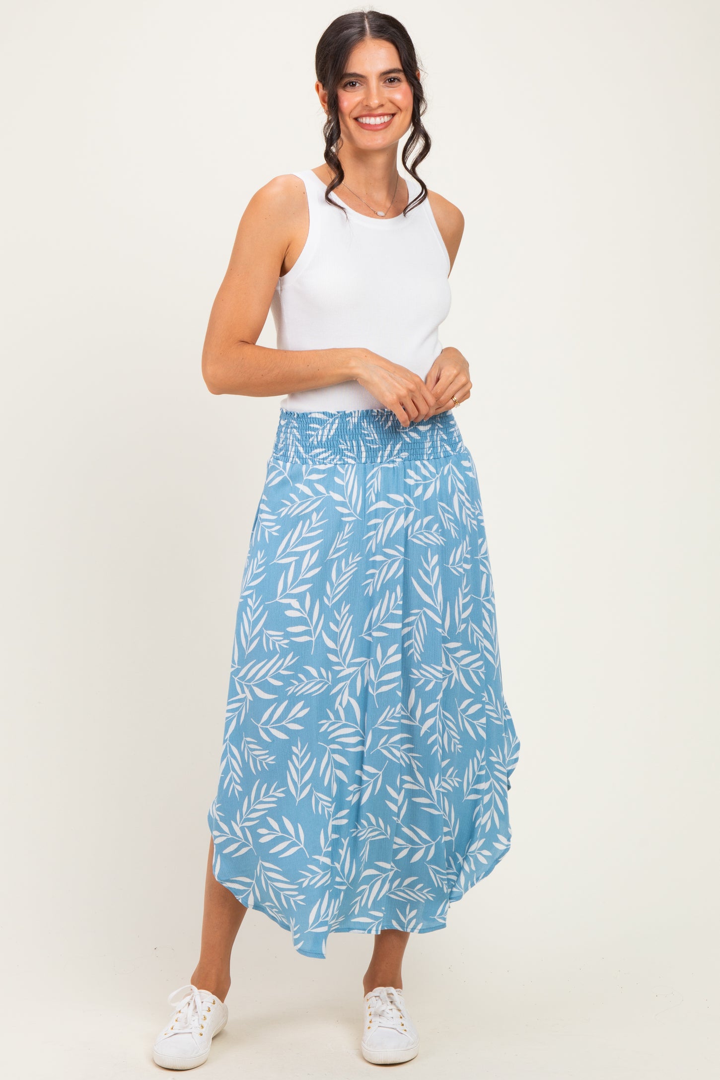 woman wearing a white tank top and a blue patterned maxi skirt with an elastic waistband and a flowy silhouette