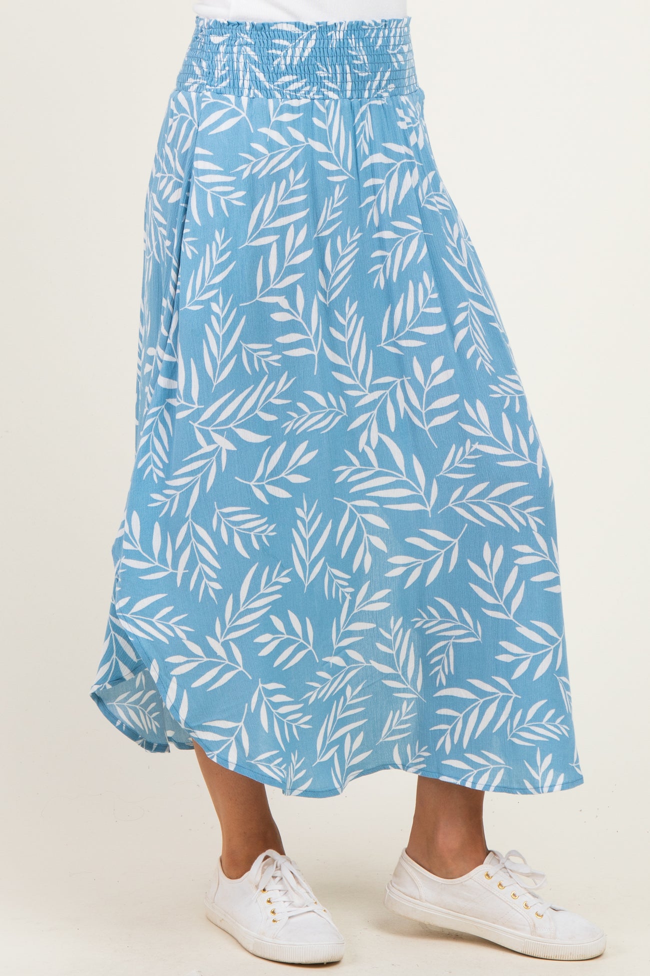 woman wearing a blue floral print maxi skirt with an elastic waistband and white sneakers