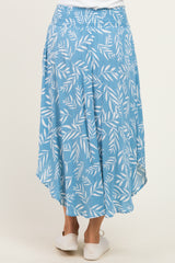 woman wearing a light blue skirt with a leaf print and an asymmetrical hemline, showing the back view