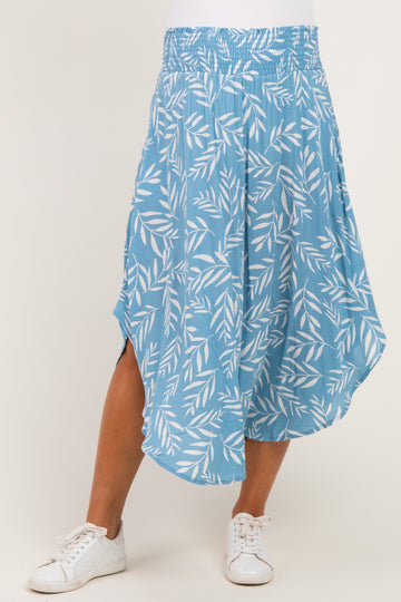 woman wearing a light blue maternity skirt with a leaf pattern and side slits, paired with white sneakers