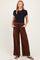 woman wearing a black short sleeve maternity top and brown wide-leg maternity pants with pockets