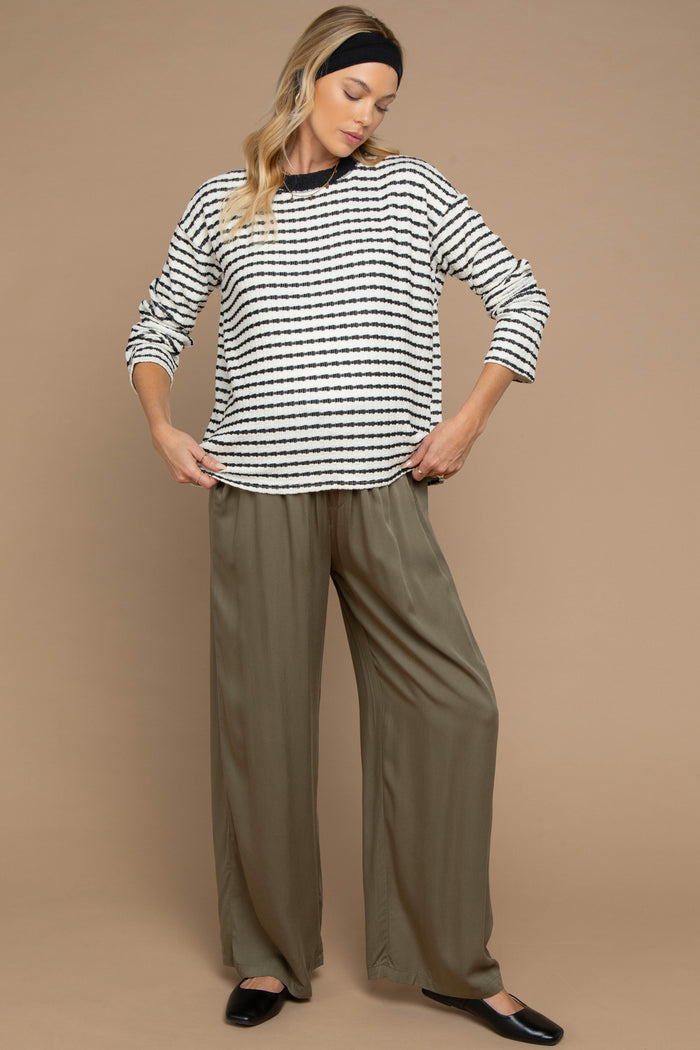 woman wearing a striped maternity top with long sleeves and loose olive green maternity pants
