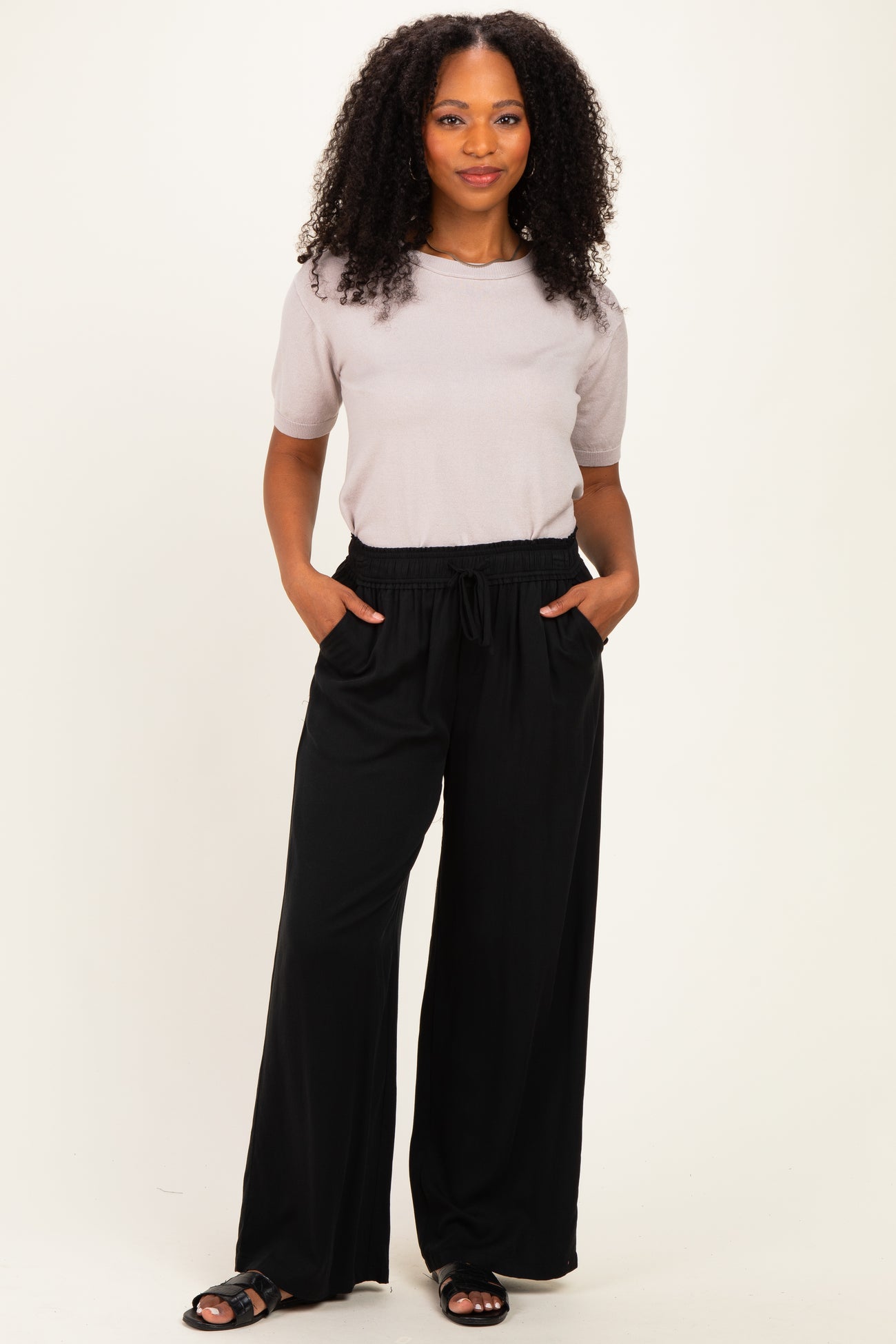 woman wearing a light gray short sleeve top and black wide-leg pants with pockets