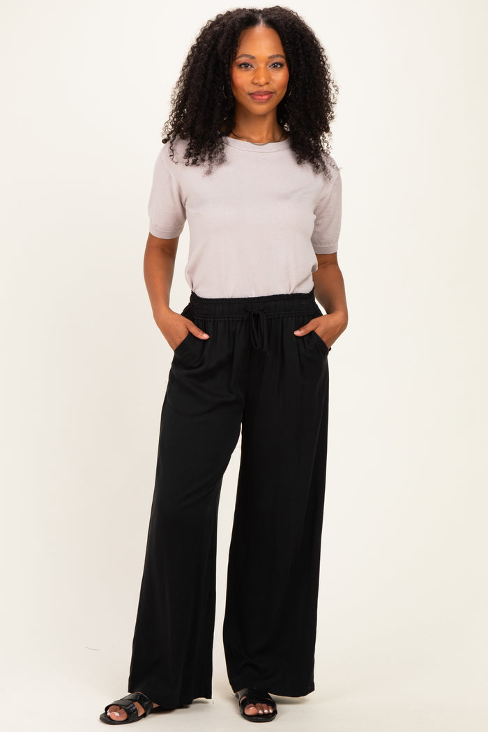 woman wearing a light gray short sleeve top and black wide-leg pants with pockets
