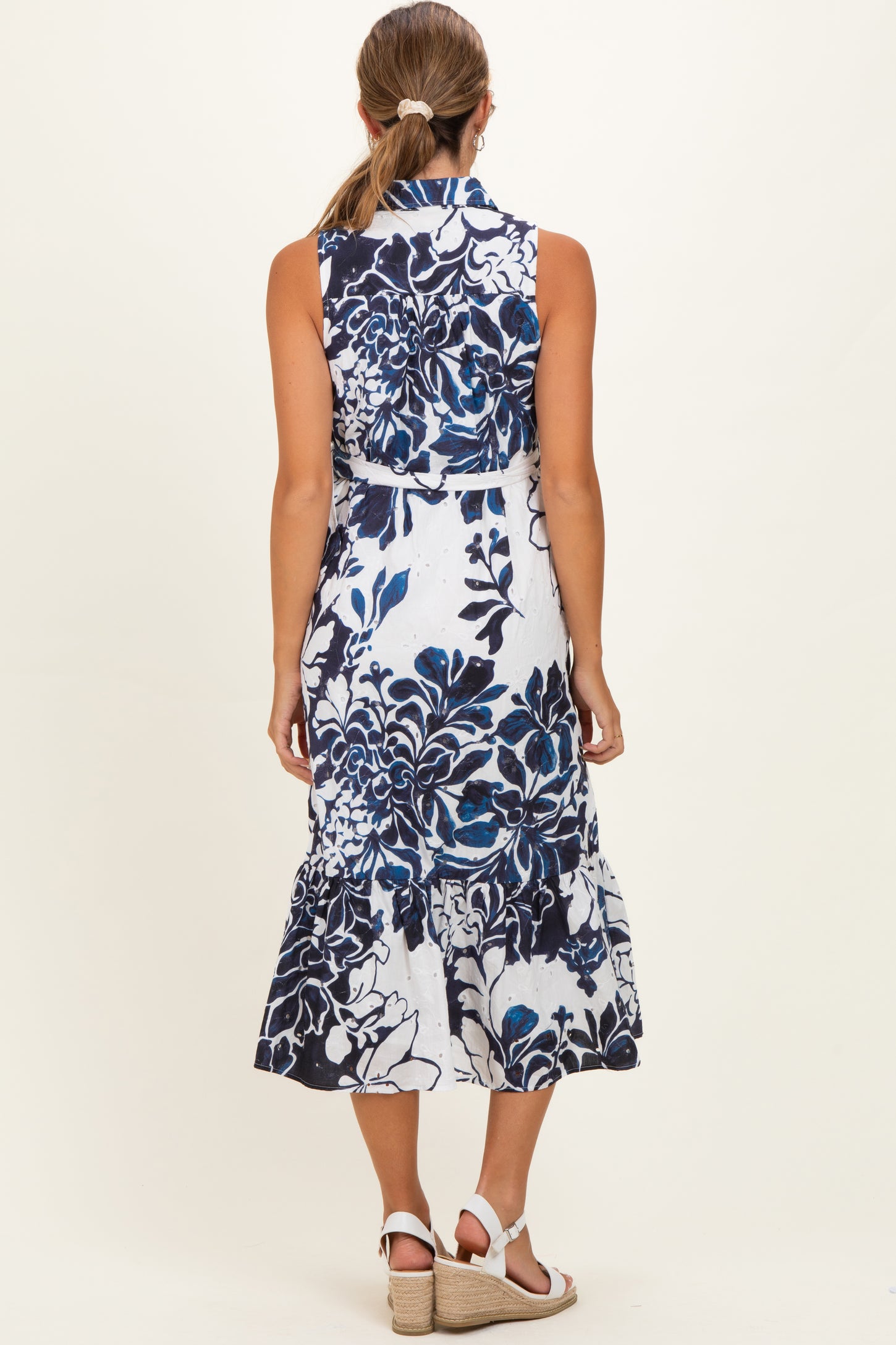 woman wearing a blue and white floral maternity dress with ruffled hem, seen from the back