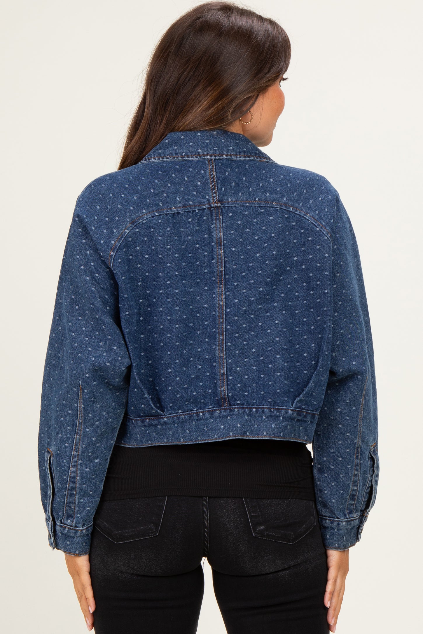 woman wearing a dark wash cropped denim jacket with a dotted pattern over a black top and jeans
