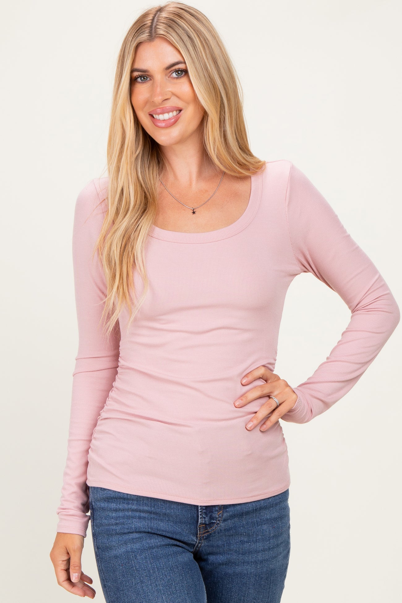woman wearing a light pink long sleeve ribbed top and blue jeans