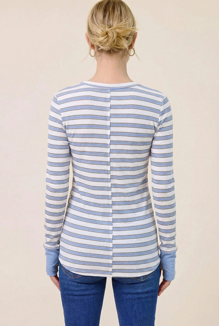 woman wearing a white and blue striped long sleeve shirt with a buttoned back and blue cuffs, seen from the back