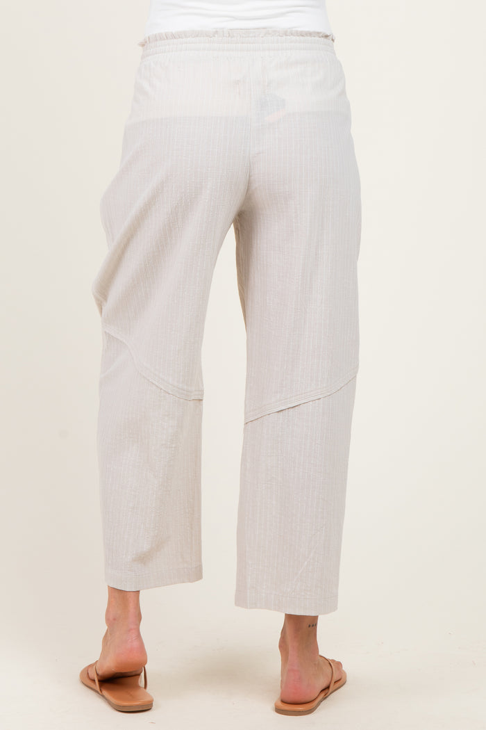 woman wearing light beige maternity pants with a relaxed fit and elastic waistband, viewed from the back